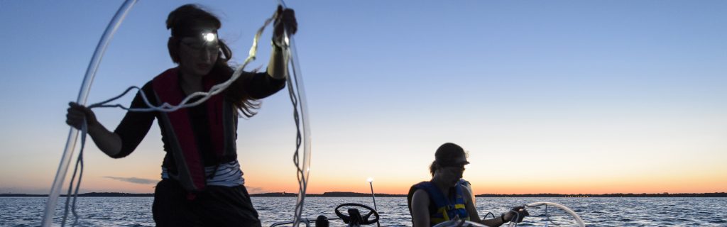 students sampling lake water on boat