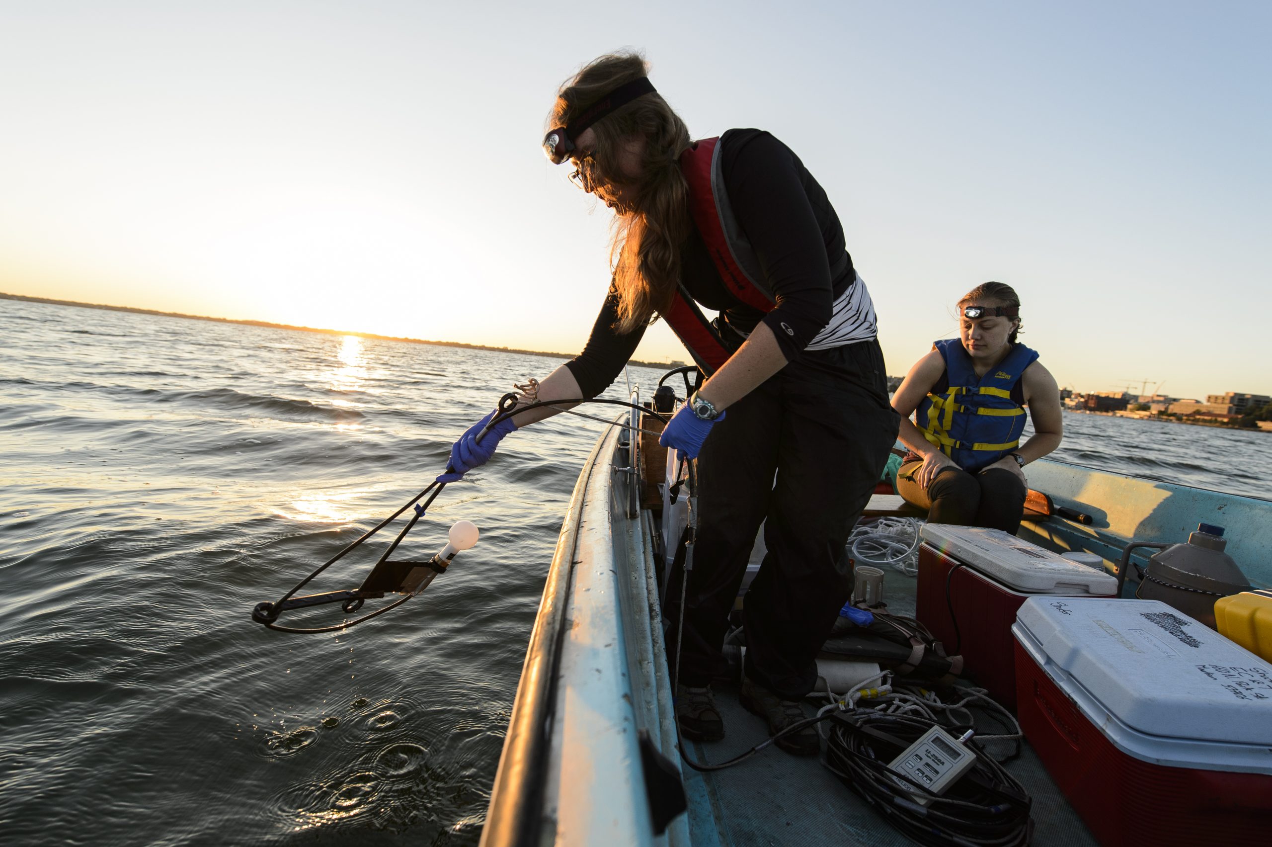 students on a boat sampling lake water